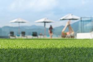 Artificial Grass with a man and umbrellas in the background